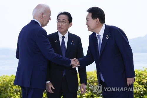 South Korean President Yoon Suk Yeol (R), U.S. President Joe Biden (L) and Japanese Prime Minister Fumio Kishida greet each other ahead of their trilateral talks in Hiroshima, Japan, on May 21, 2023, in this photo provided by the AP. (Yonhap)