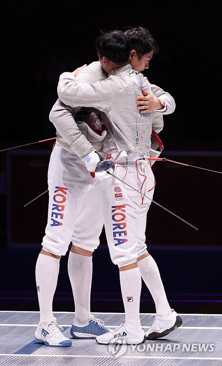 South Korea's Gu Bon-gil (R) and Oh Sang-uk hug each other after the all-Korean final of the men's individual sabre fencing at Hangzhou Dianzi University Gymnasium in Hangzhou, China, during the 19th Asian Games. (Yonhap)