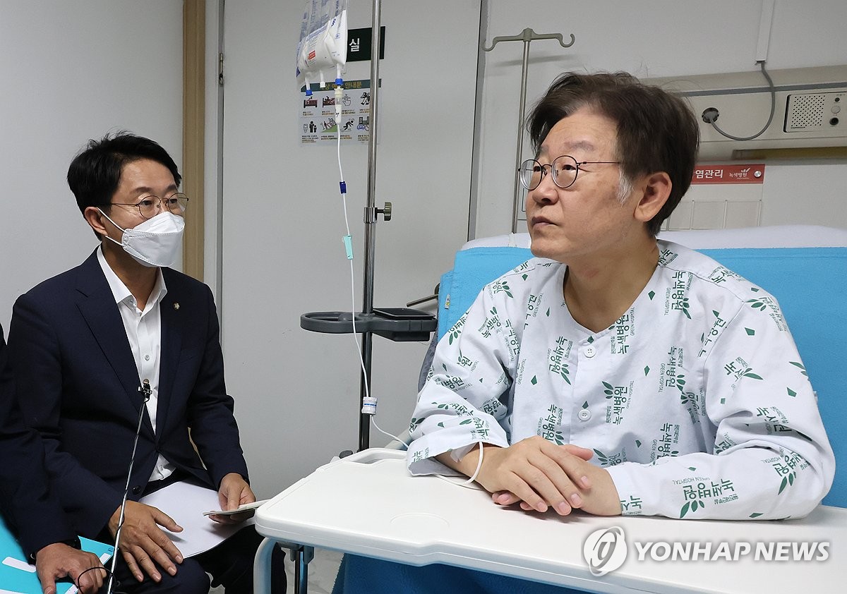 Lee Jae-myung, chair of the Democratic Party, is briefed by a party official on Sept. 28, 2023, at a hospital in Seoul where he is under treatment following a 24-day hunger strike. (Yonhap)