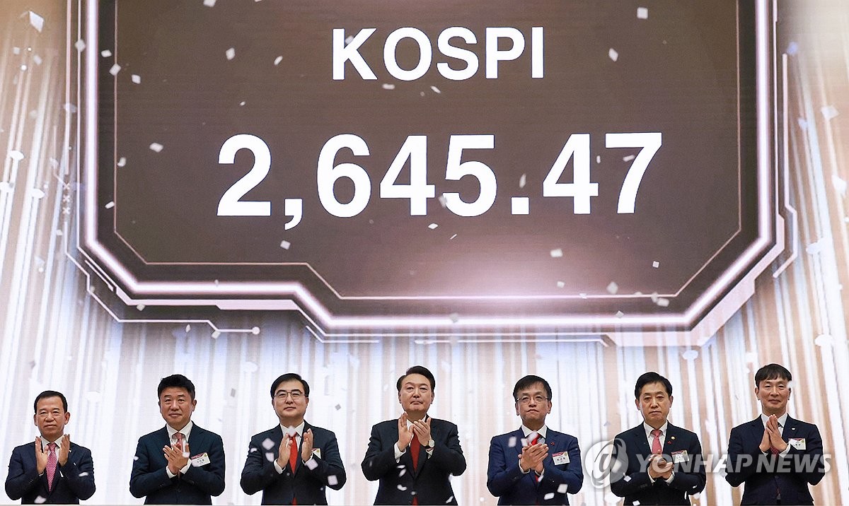 President Yoon Suk Yeol (C) claps after pressing a button signaling the start of trading on the first trading day of the new year at the Seoul office of the Korea Exchange on Jan. 2, 2023. (Yonhap)