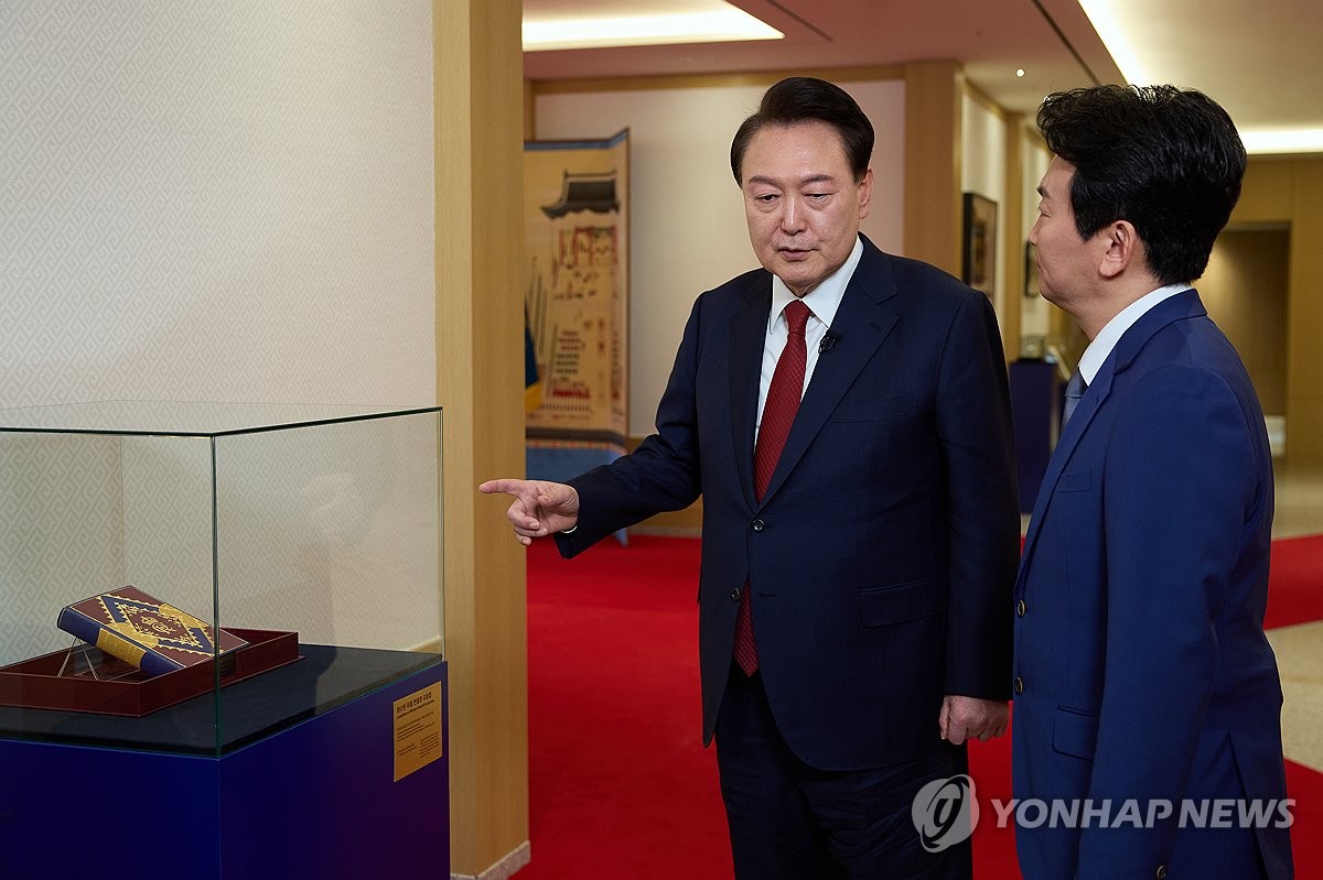 El presidente Yoon Suk Yeol (izq.) presenta una recopilación de los discursos de Winston Churchill, regalada por el rey Carlos III durante una visita de estado a Gran Bretaña en noviembre de 2023, a un presentador de KBS después de grabar una entrevista especial con la emisora ​​estatal en la oficina presidencial en Seúl el 4 de febrero de 2024, en esta fotografía proporcionada por la oficina.  (FOTO NO EN VENTA) (Yonhap)