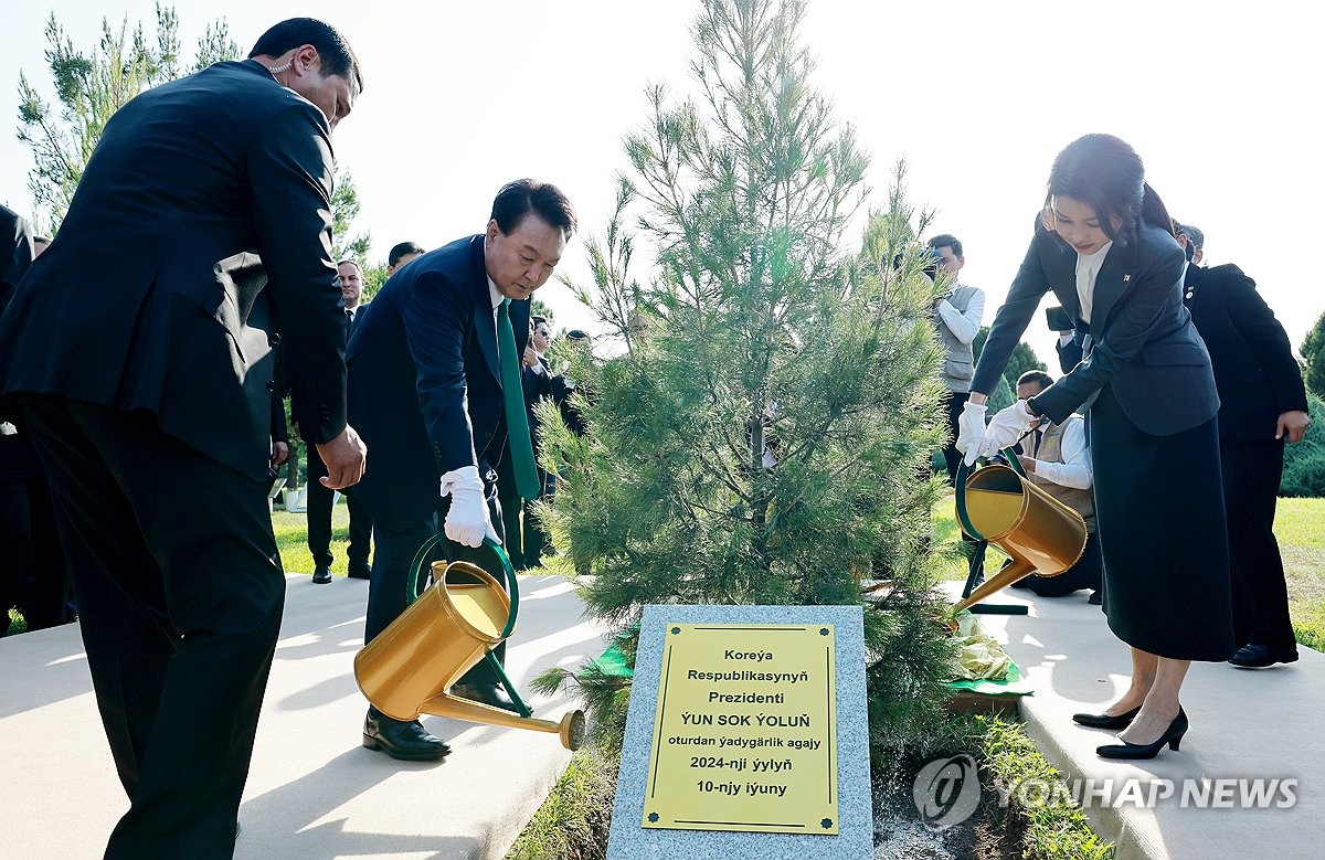 President Yoon Suk Yeol (L) and first lady Kim Keon-hee (R) water trees after a tree-planting ceremony at a park near the Independence Monument in Ashgabat, Turkmenistan on June 10, 2024. (Pool photo) (Yonhap) 