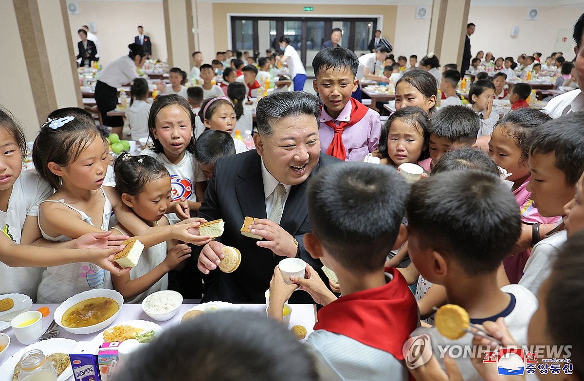 Esta fotografía, publicada por la Agencia Central de Noticias de Corea del Norte, el 16 de agosto de 2024, muestra al líder norcoreano Kim Jong-un (centro) reunido con niños que llegaron a Pyongyang el día anterior para alojarse en un albergue debido a las últimas inundaciones en las zonas fronterizas del norte del país. (Para uso exclusivo en la República de Corea. No se permite su distribución) (Yonhap)