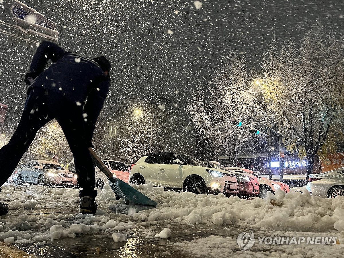 Una persona quita la nieve de una carretera cerca del Palacio Gyeongbok en Seúl el 27 de noviembre de 2024, después de que partes de la ciudad recibieran más de 15 centímetros de nieve durante la noche. (Yonhap)