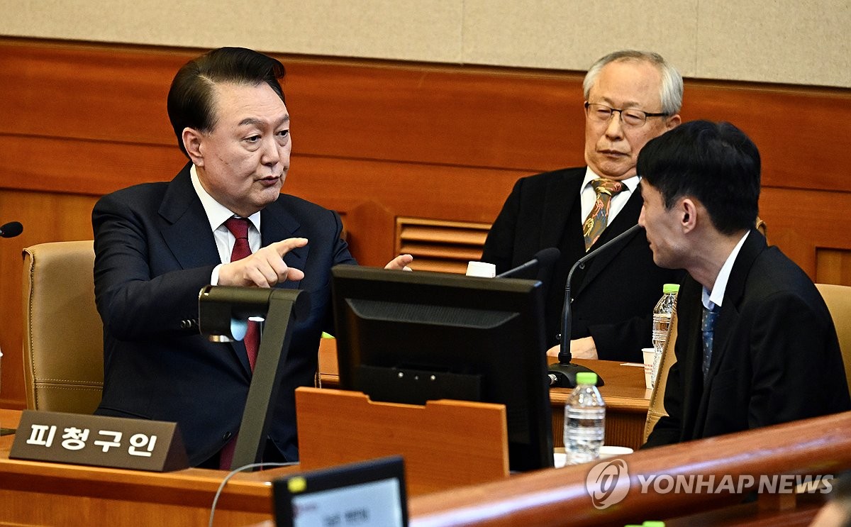 El presidente Yoon Suk Yeol (izq.) habla con sus abogados en el Tribunal Constitucional de Seúl el 23 de enero de 2025, durante la cuarta audiencia de su juicio político por su breve imposición de la ley marcial en diciembre. (Foto de la piscina) (Yonhap)