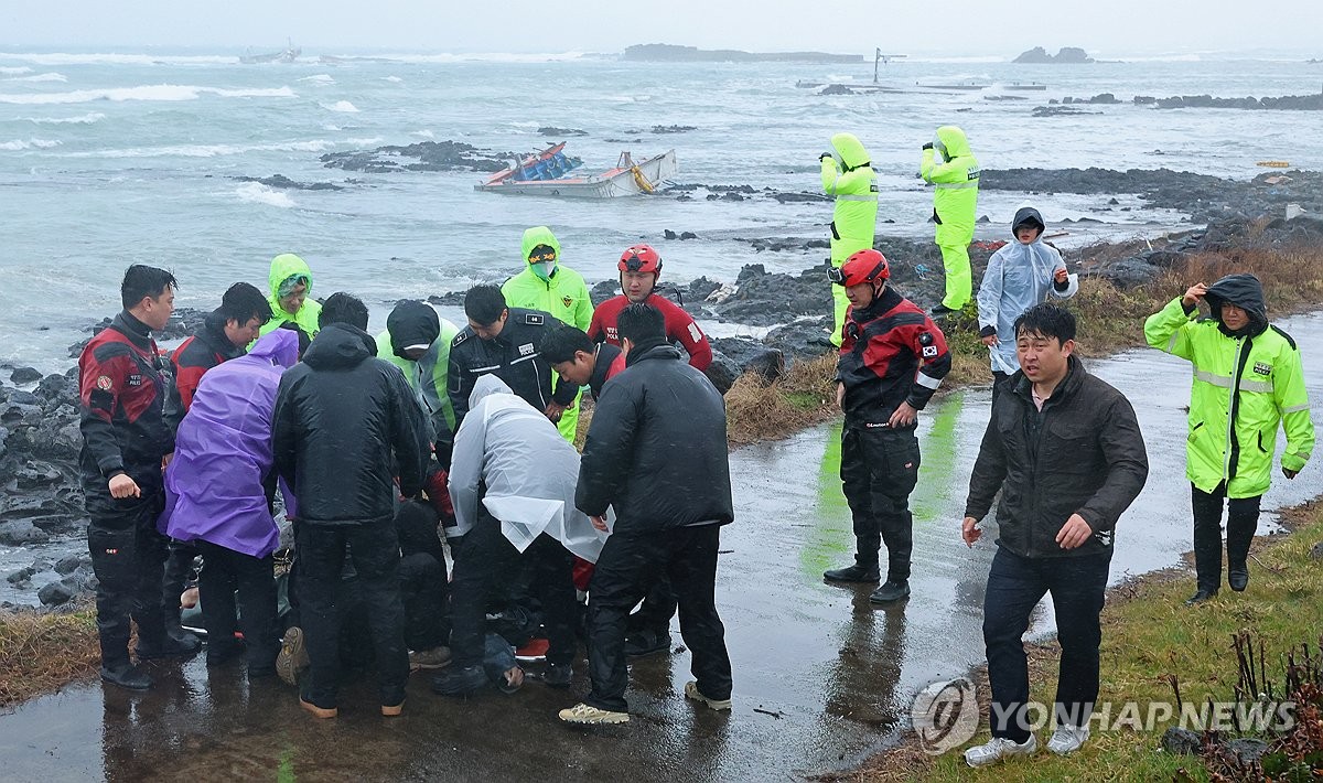 Los funcionarios de la Guardia Costera mueven a un miembro de la tripulación rescatado en una camilla a una ambulancia el 1 de febrero de 2025, después de que dos botes de pesca que transportaban a 15 personas encallan en aguas frente a la isla sur de Jeju. (Yonhap)