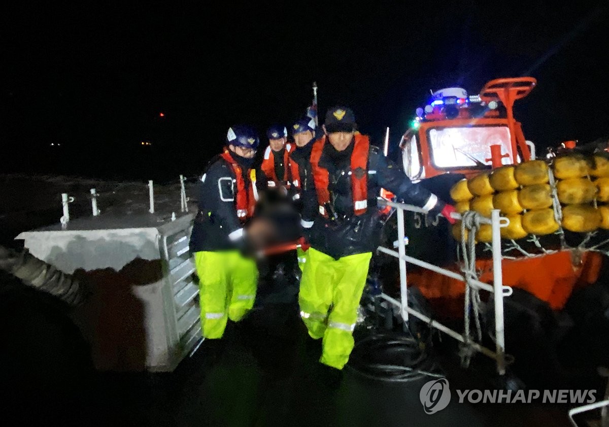 Los funcionarios de la Guardia Costera transportan a un miembro de la tripulación rescatado de un buque pesquero que se hundió en aguas frente a Yeosu, 316 kilómetros al sur de Seúl, el 9 de febrero de 2025, en esta foto proporcionada por la Guardia Costera. (Foto no a la venta) (Yonhap)