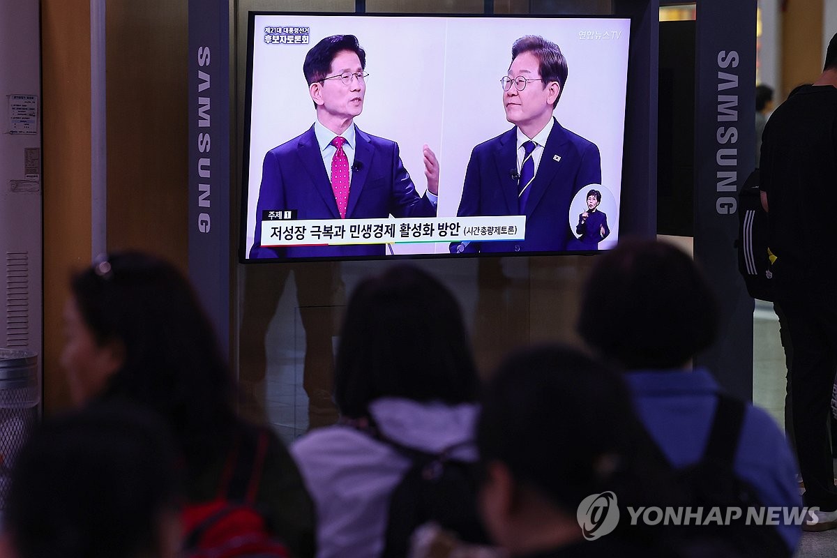 People watch the televised debate between Democratic Party presidential candidate Lee Jae-myung (R) and his People Power Party rival Kim Moon-soo at Seoul Station in the capital on May 18, 2025. (Yonhap)